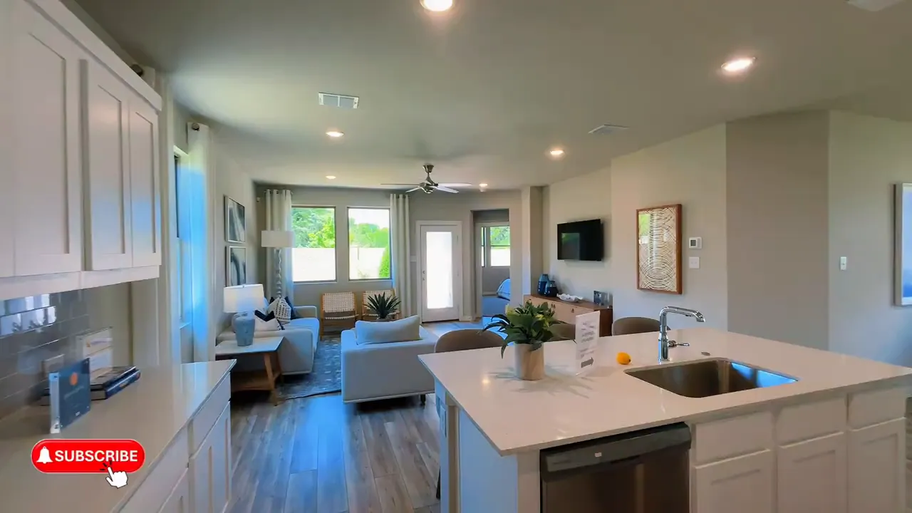 Open kitchen with large island, white cabinets, and living room beyond
