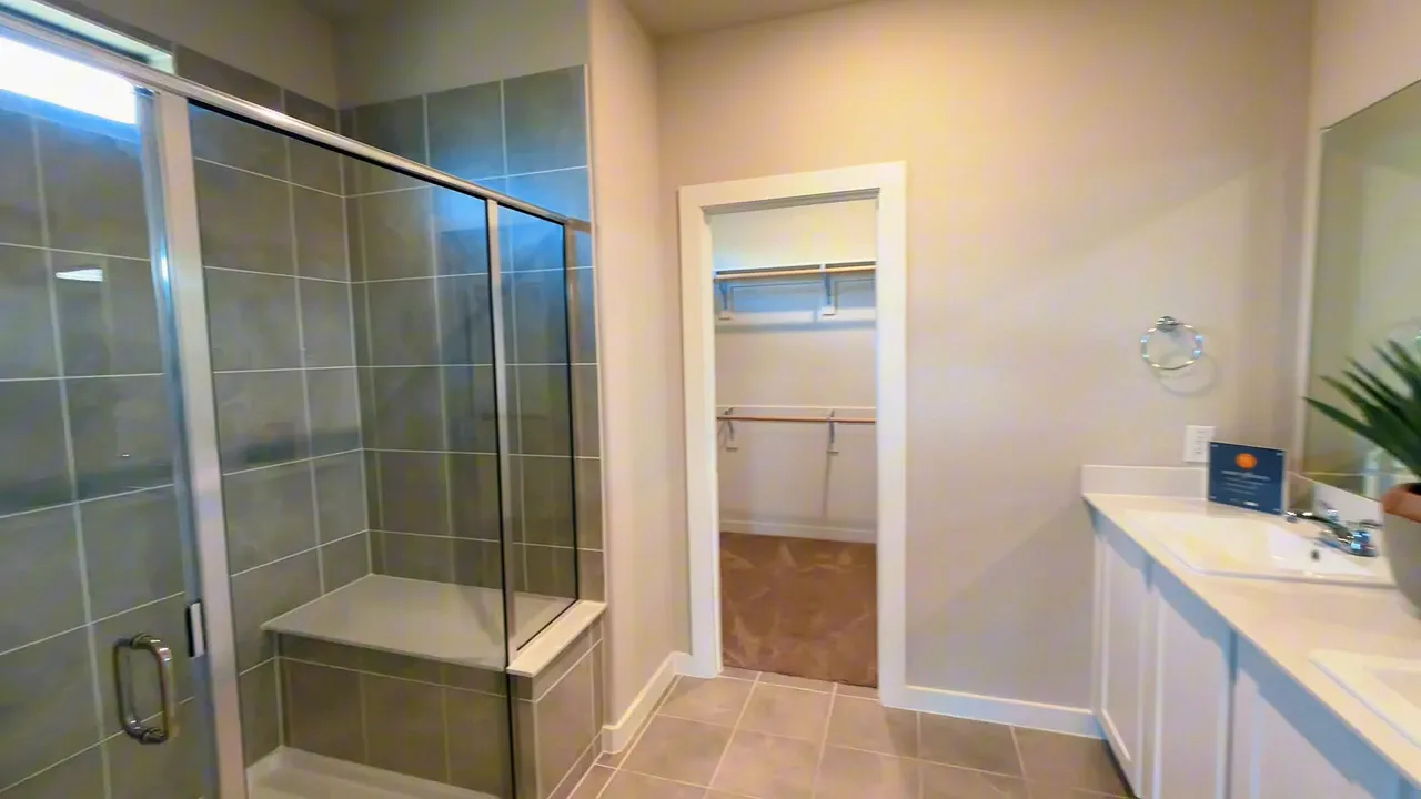 Primary bathroom with glass walk in shower and doorway to closet
