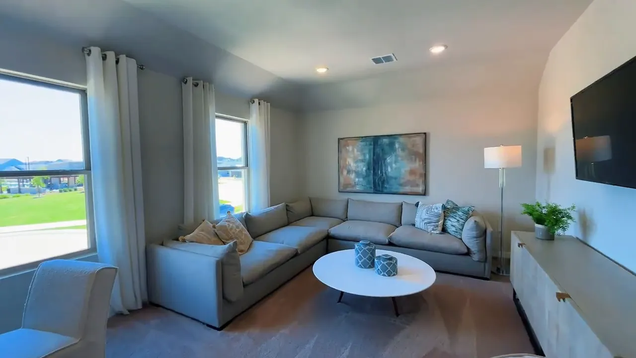 Upstairs game room with sectional sofa, round coffee table, and wall art