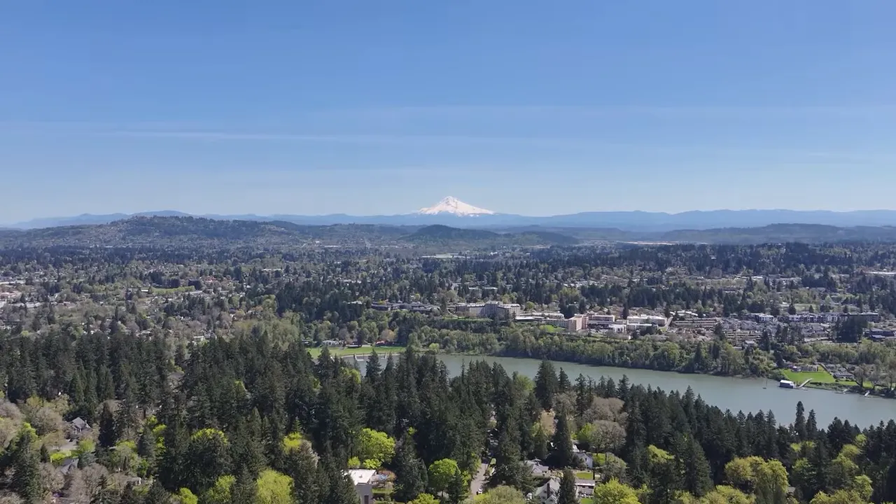 Wide aerial panorama of Portland-area suburbs with a lake and Mount Hood in the distance