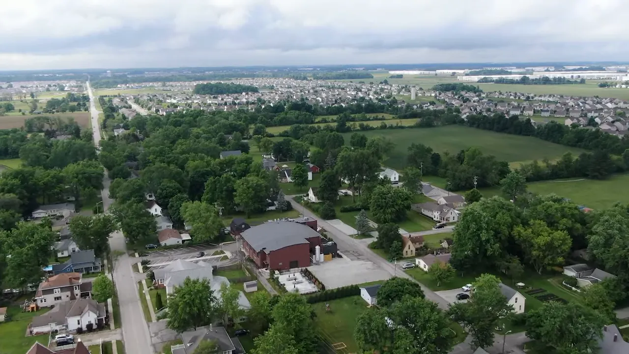 High-resolution aerial photograph of expanding suburban neighborhoods, roads, and surrounding green space near Indianapolis