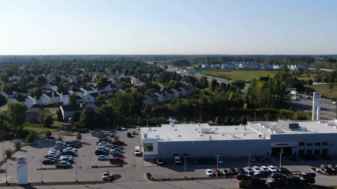 High-resolution aerial photograph of suburban neighborhoods, parking lots, retail building, and open land near Indianapolis.