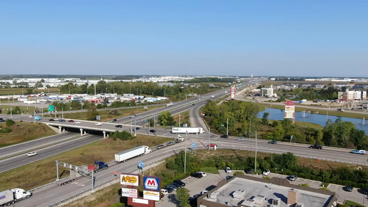 Aerial view of a highway interchange with nearby retail centers, new subdivisions and open land near Indianapolis.