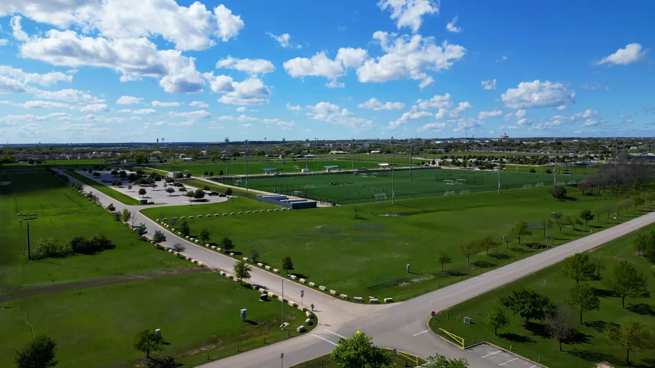 Aerial view of Old Settlers Park in Round Rock, Texas showing sports fields, paths, and surrounding park area