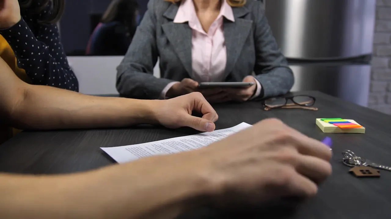 Hands reviewing new construction contract paperwork at a meeting table