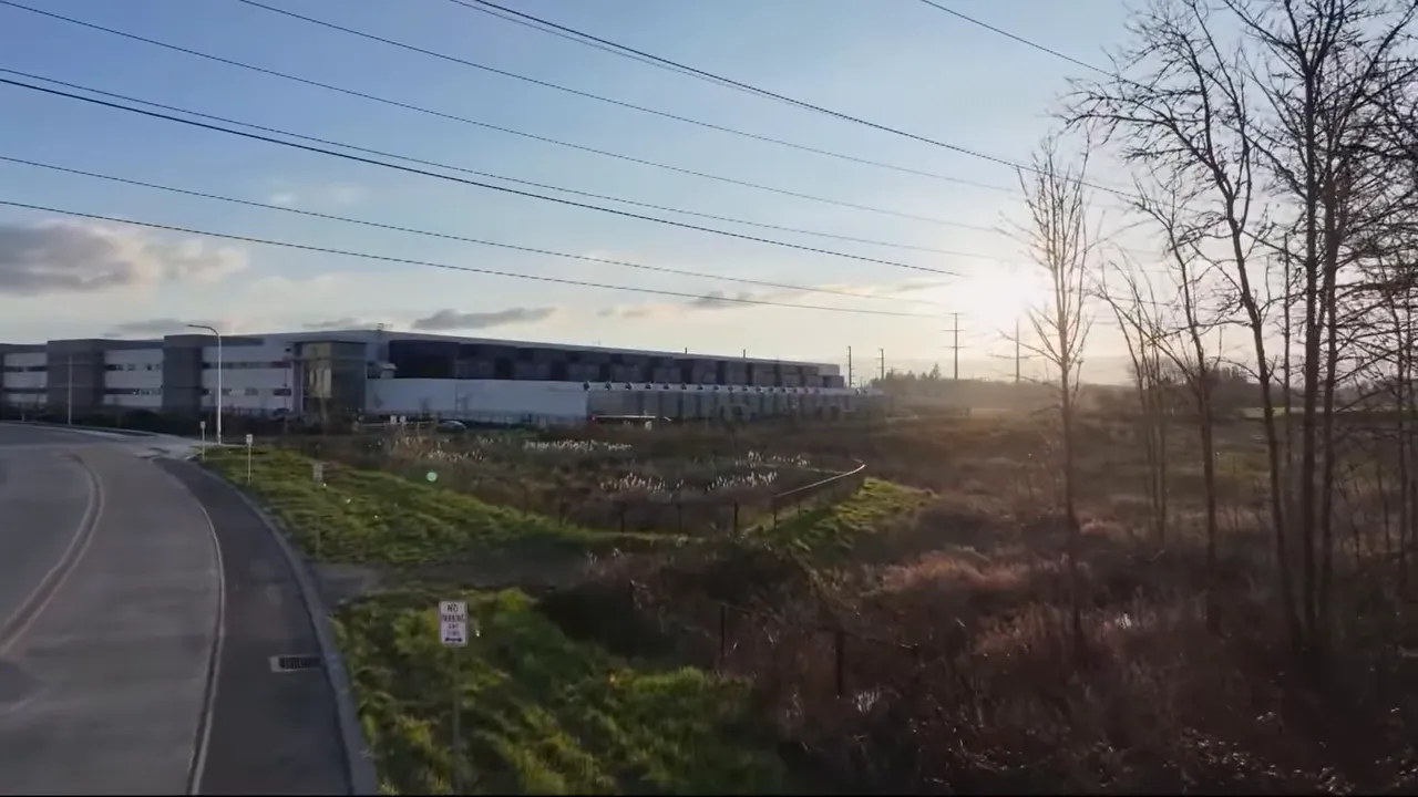 Road and transmission lines beside a large data center campus in an open area
