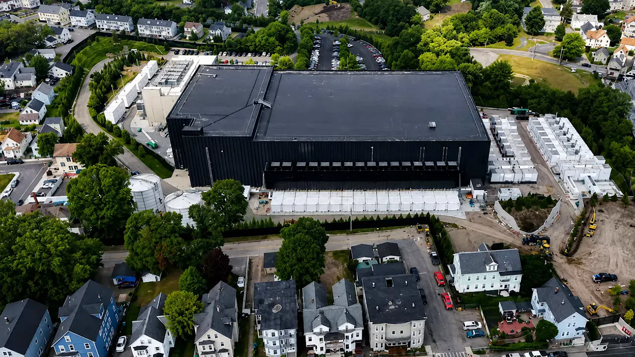 Aerial image of a large black data center surrounded closely by residential homes