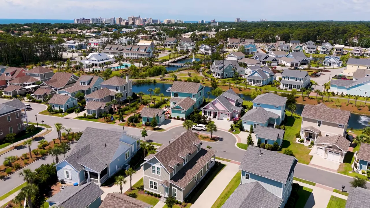 Aerial shot of a Myrtle Beach neighborhood showing houses, ponds, streets and the distant ocean skyline.
