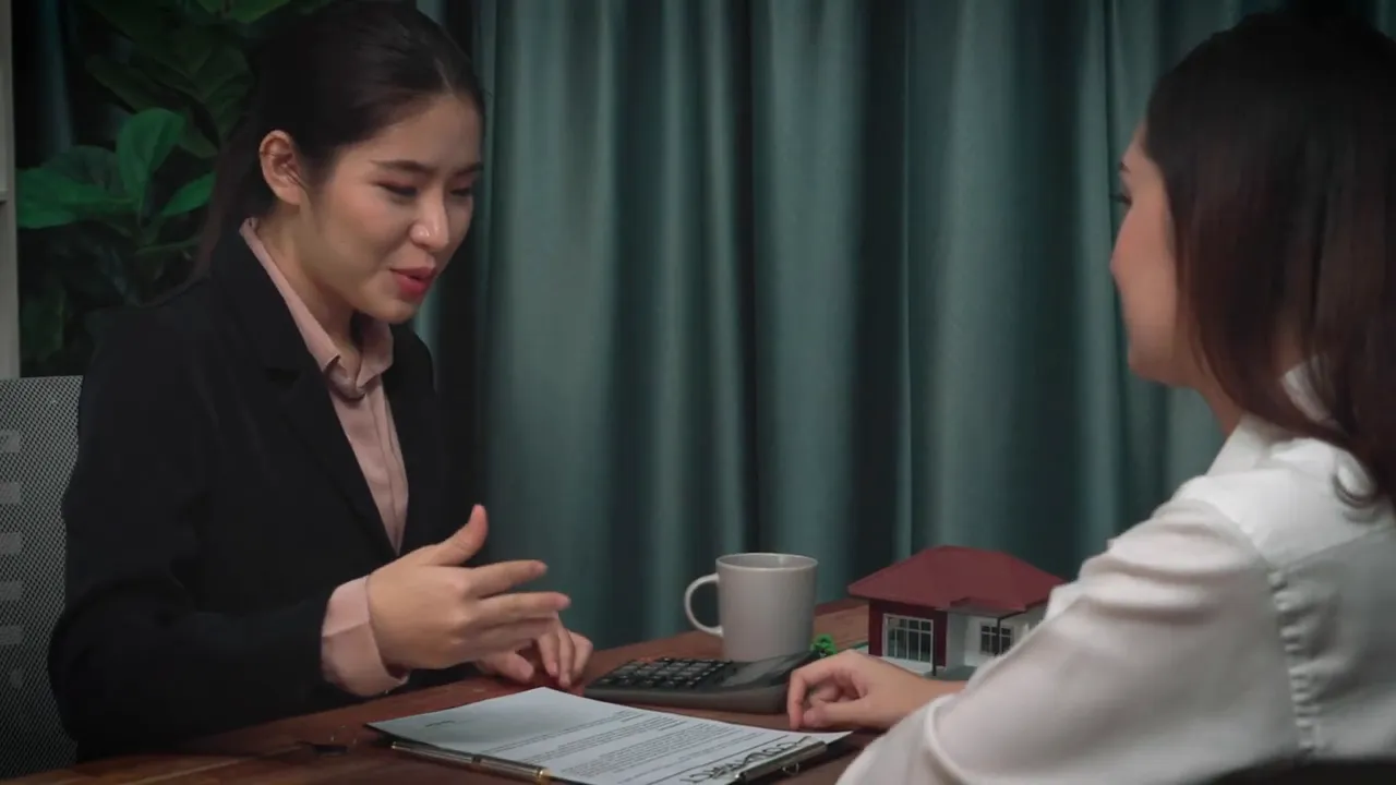 Buyer discussing terms with real estate agent at a table with house model and documents
