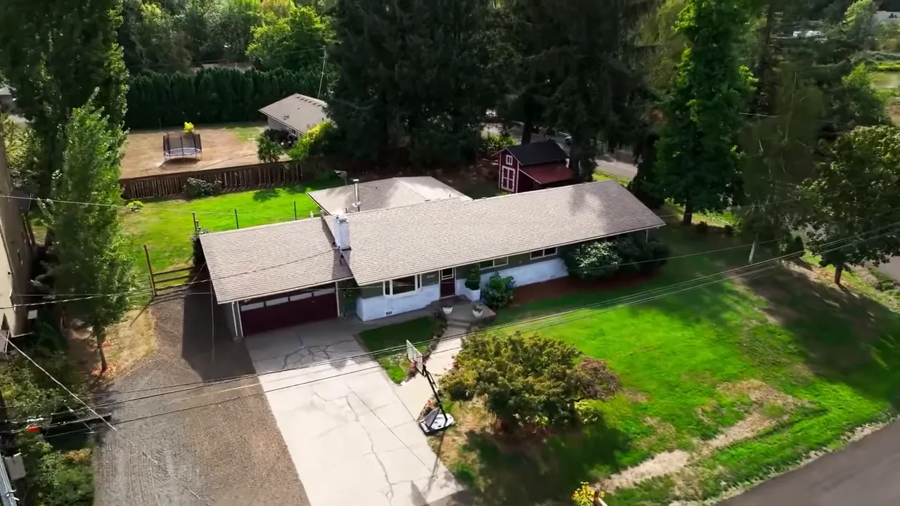 Aerial view of a single story home on a corner lot with green yard