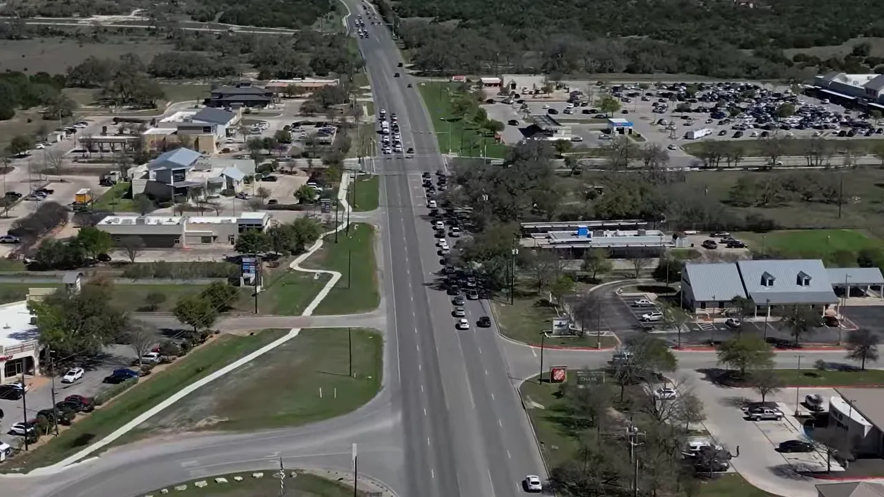 Aerial view of a road through Dripping Springs with surrounding businesses and parking
