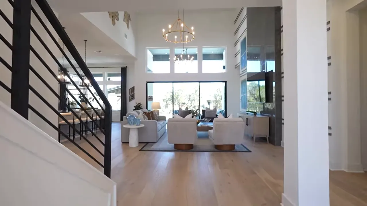 Open-concept living room with large windows and staircase in a Dripping Springs home