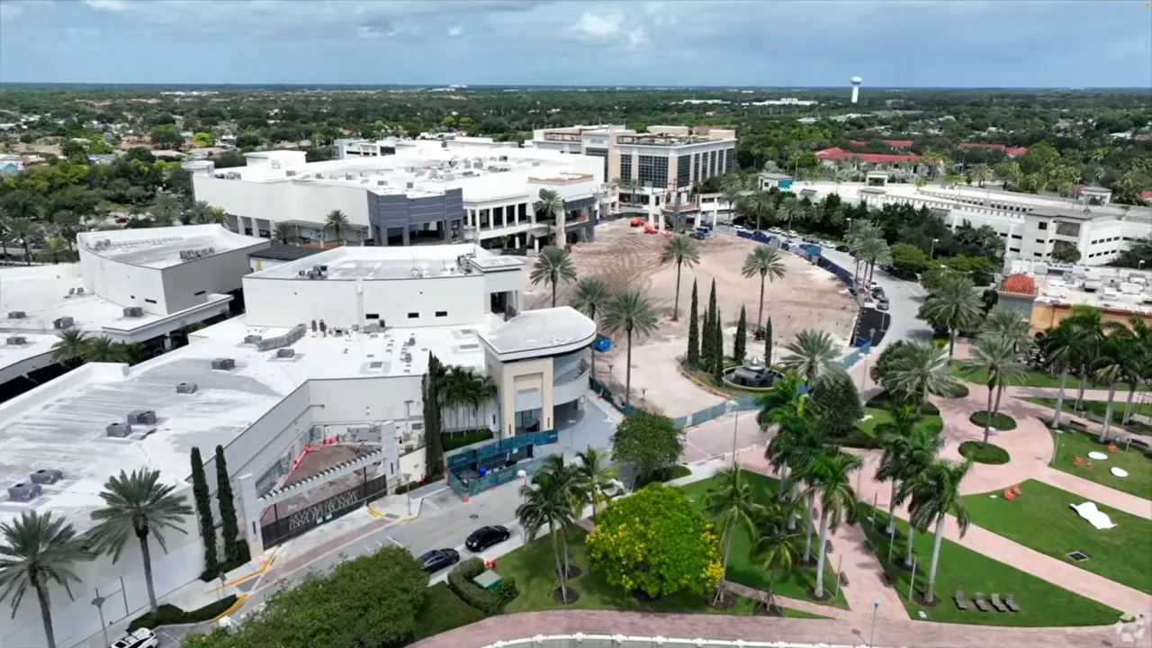 Open air shopping area with storefronts and palm lined walkways