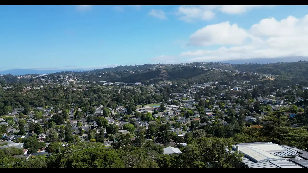 wide aerial view of hillside neighborhoods surrounded by trees