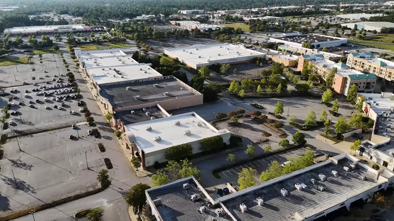 Aerial view of a large shopping center with parking lots and storefronts