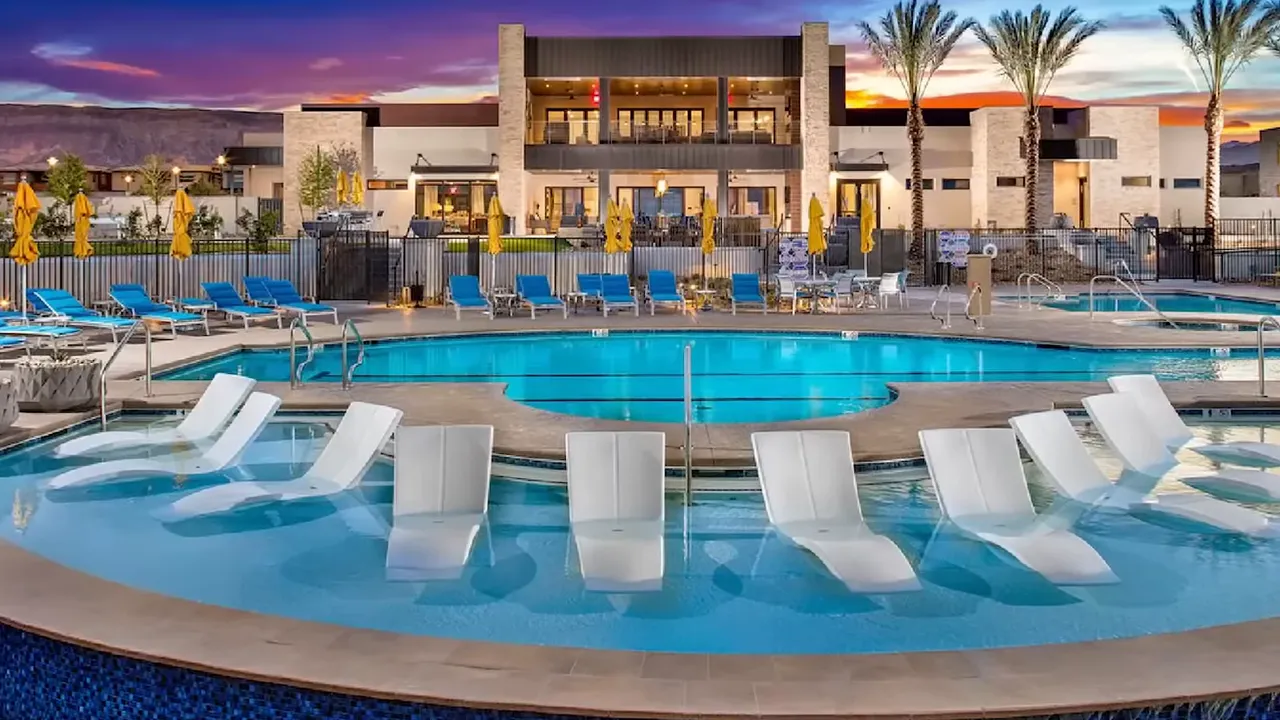 Resort pool with white lounge chairs at Trilogy clubhouse