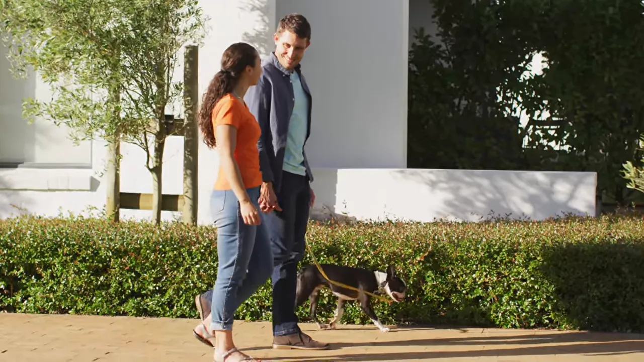 Couple walking a dog on neighborhood sidewalk in West Bend at Wolf Ranch Georgetown TX