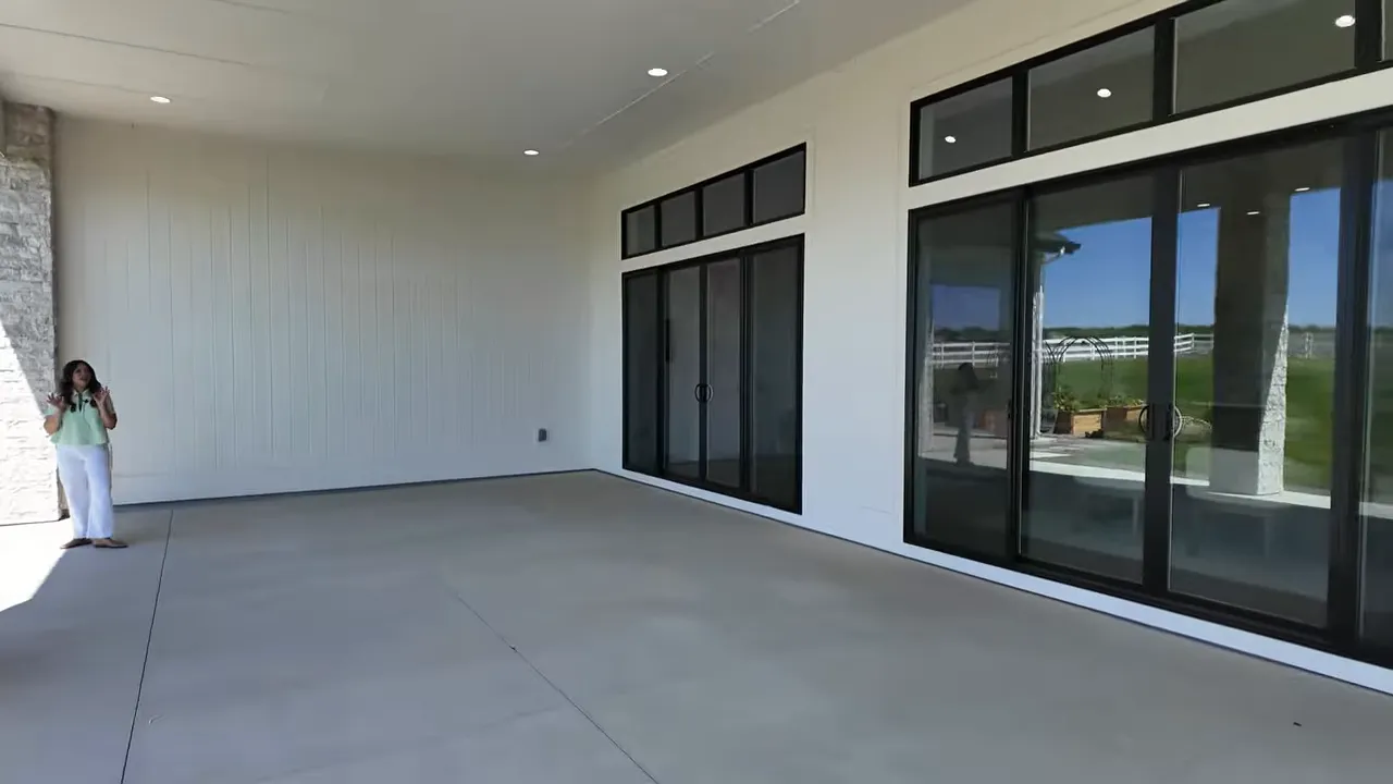 Large covered patio with black sliding glass doors and stone columns