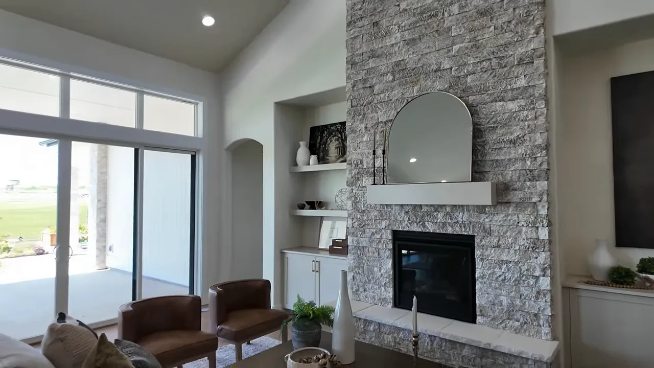 Great room with stone fireplace built-in shelves large windows and seating area