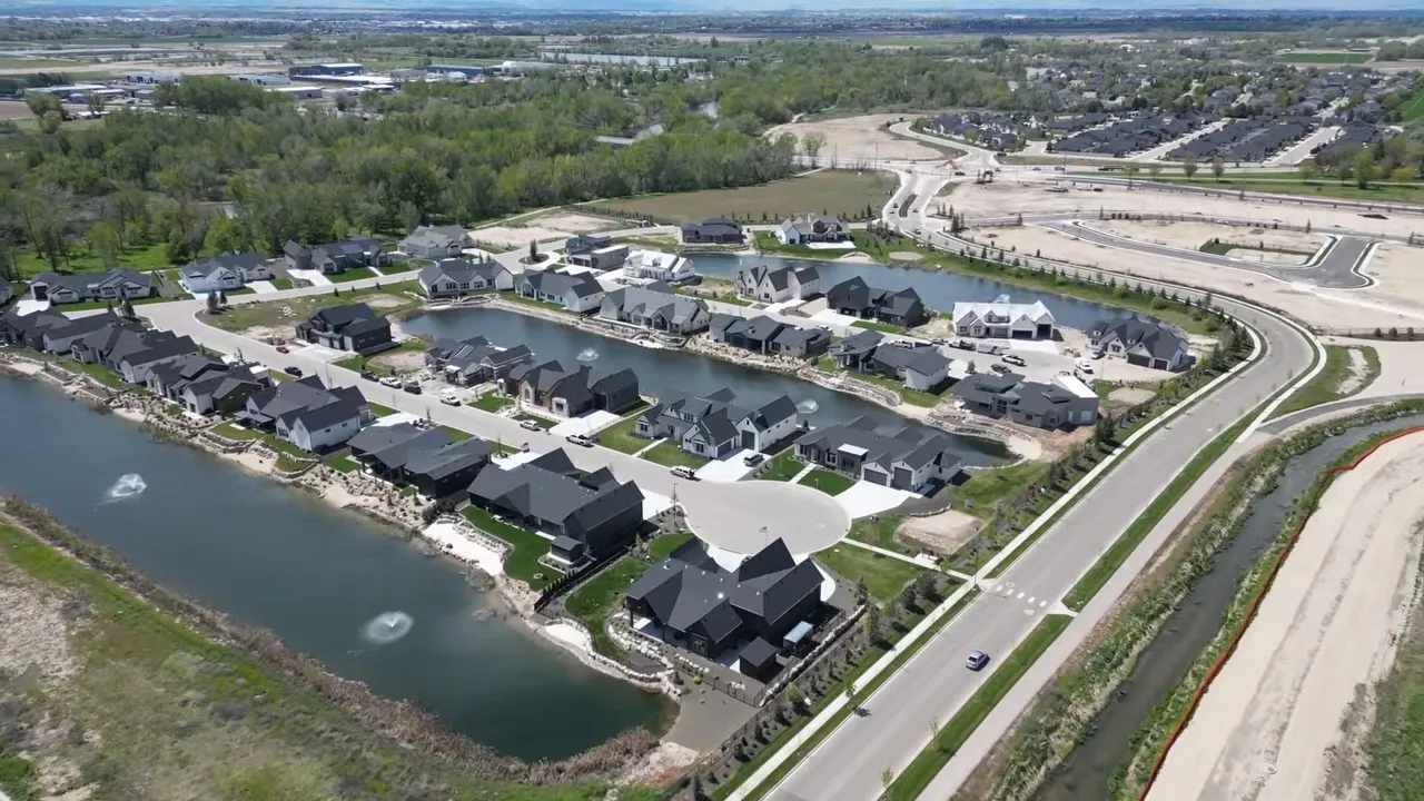 Aerial view of a Boise-area waterfront neighborhood with homes along a pond or river and landscaped lots