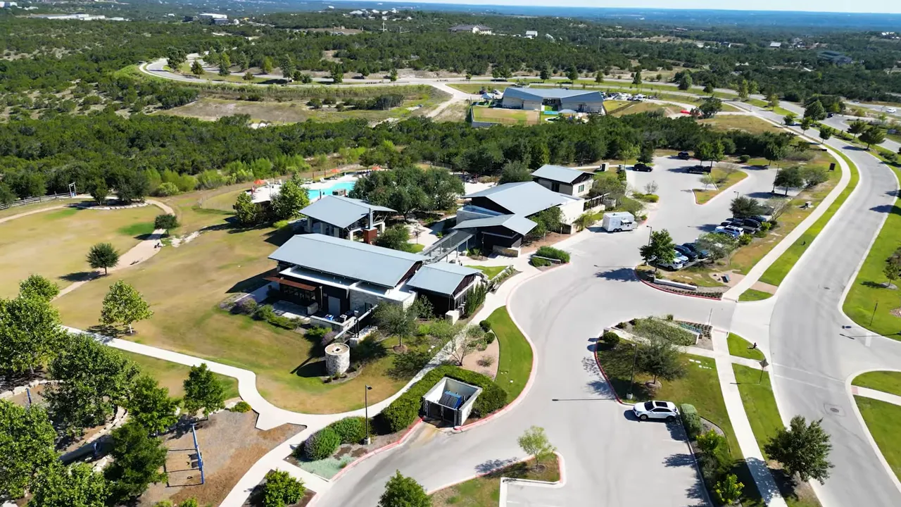 Overhead image of a neighborhood amenity center showing clubhouse buildings, pool, playground and adjacent parking and green space.