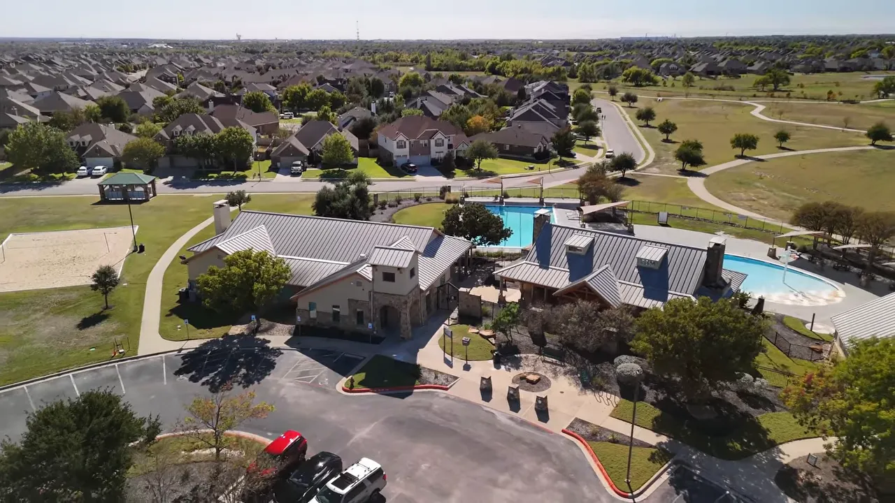 Aerial view of a suburban community with homes and a swimming pool, illustrating Austin suburbs neighborhood context