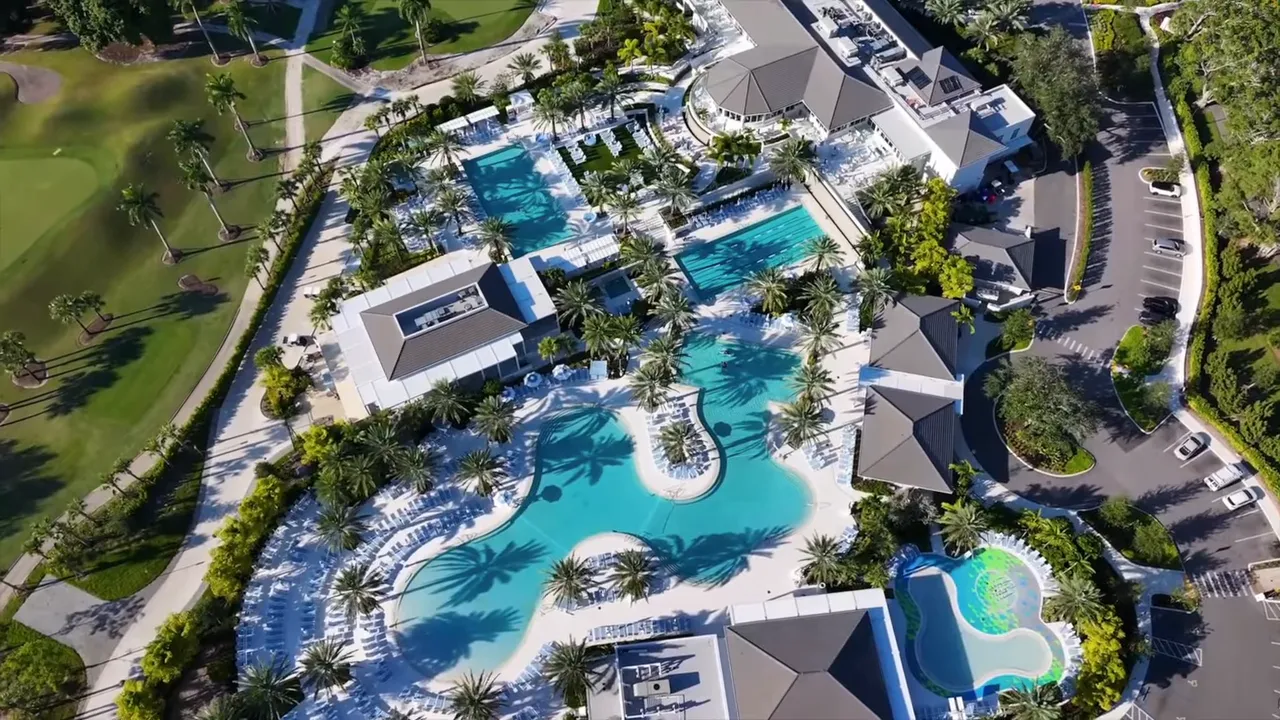 Aerial shot of Boca West pool complex showing several pools, palm trees, and surrounding buildings