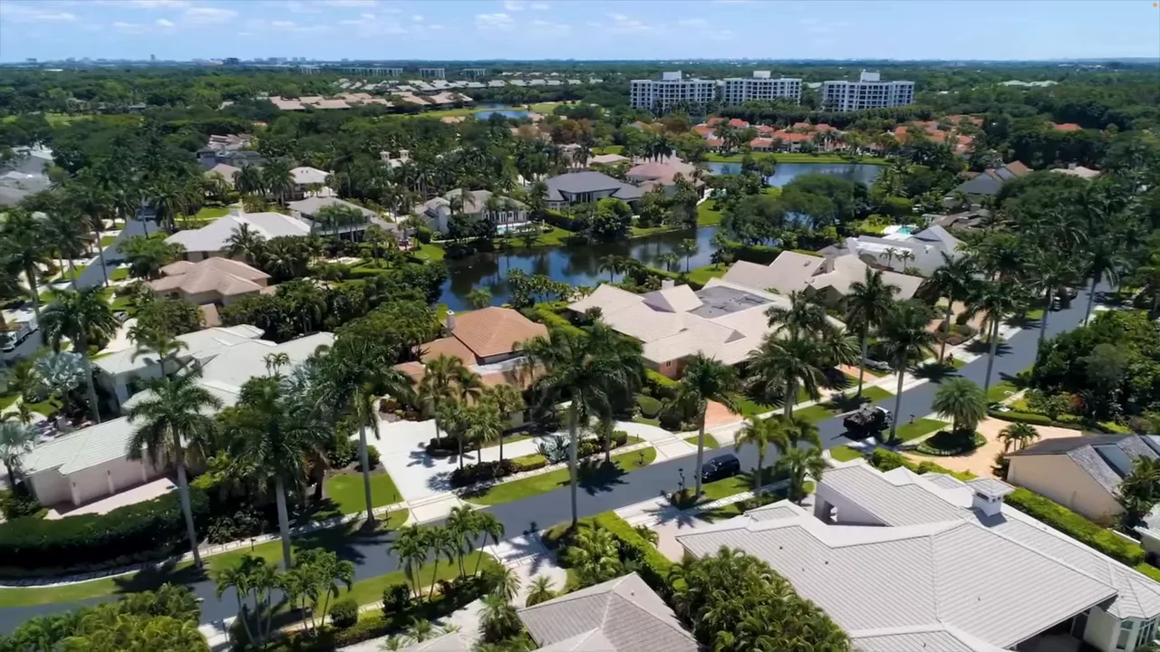 Drone aerial of Boca West neighborhood with homes, palms, and small lakes showing community layout