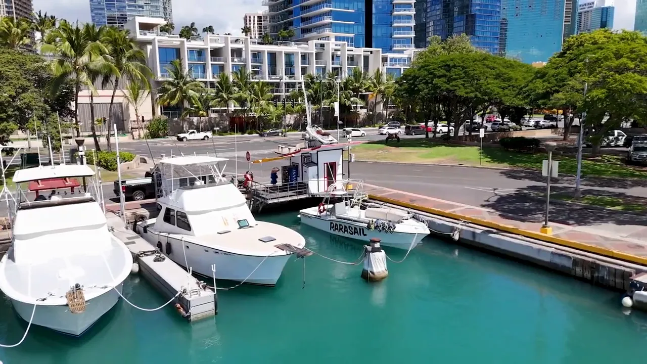 Aerial view of the parasail launch dock with boats and turquoise harbor water in Ward Village, Honolulu