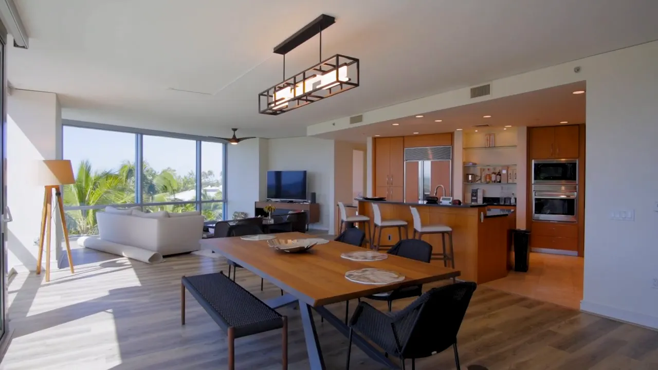 Open-plan living and dining area with large windows, dining table and kitchen