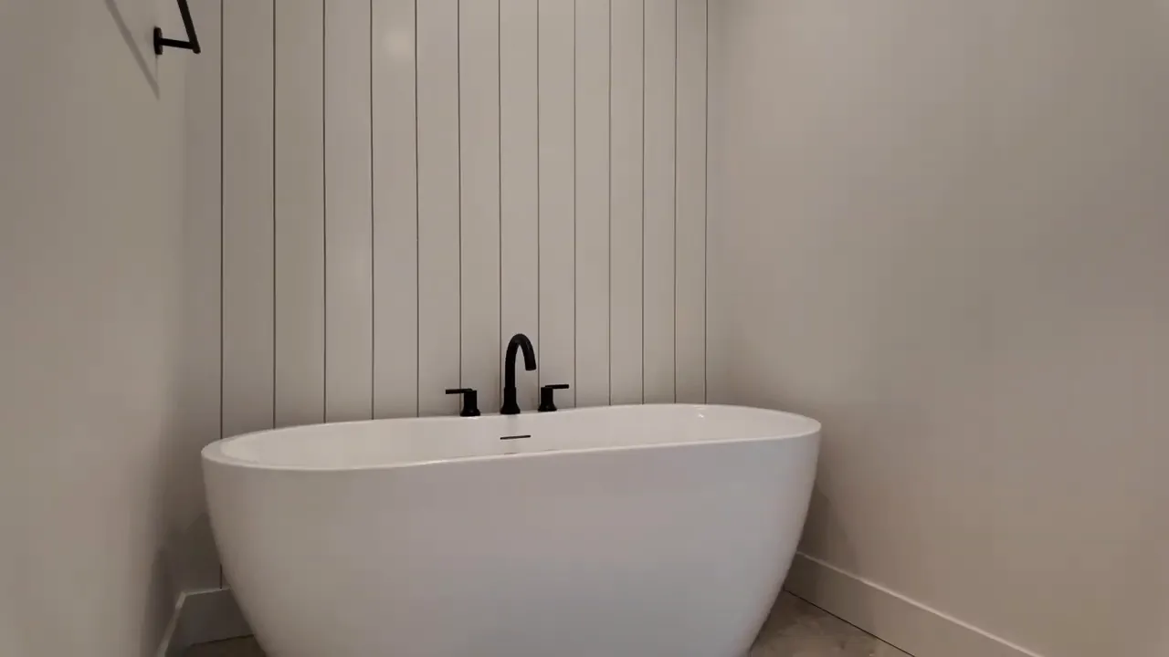 Freestanding bathtub with matte black faucet fixtures and vertical wall panels in a luxury bathroom