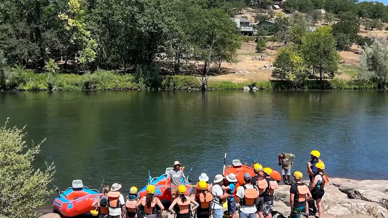 Group of rafters lined up beside calm river water