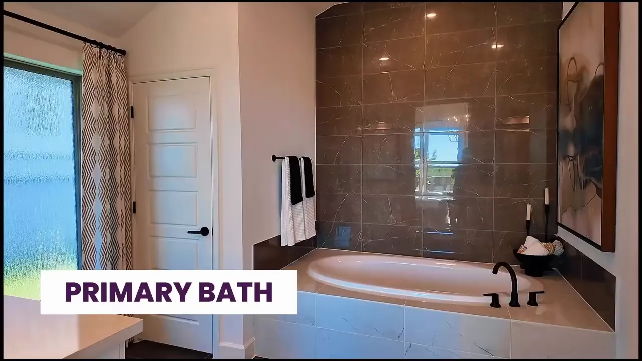 Primary bathroom with soaking tub large tile accent wall and vanity area