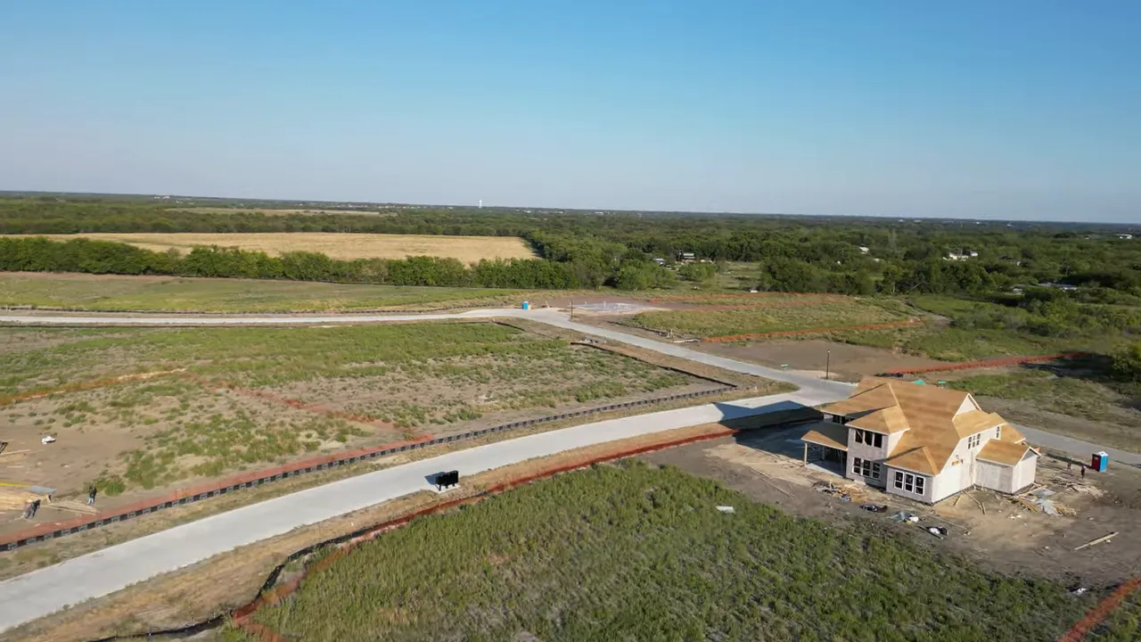 Aerial view of Ridgepark road curving past homes under construction and open land