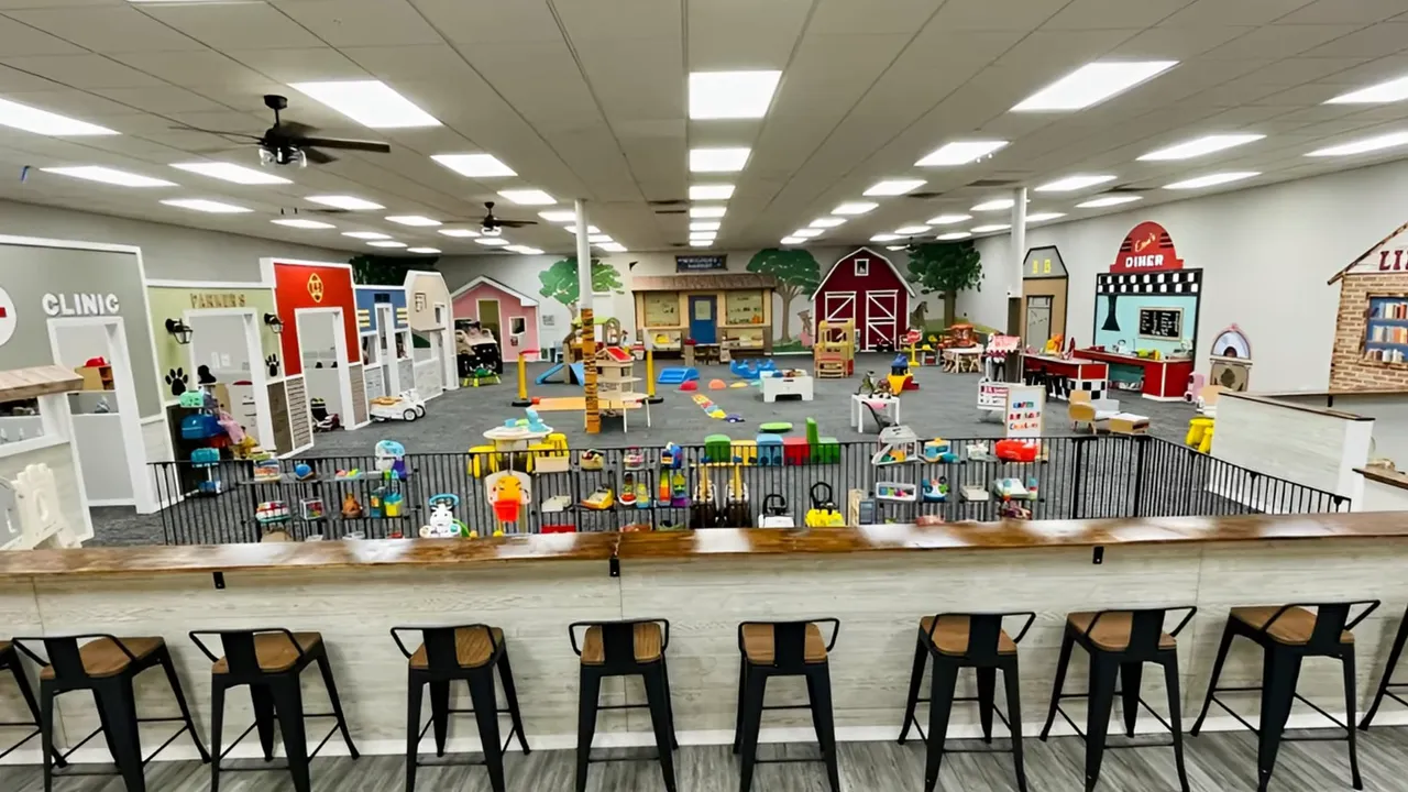 Indoor play area with colorful playhouses, stations, and children’s activities