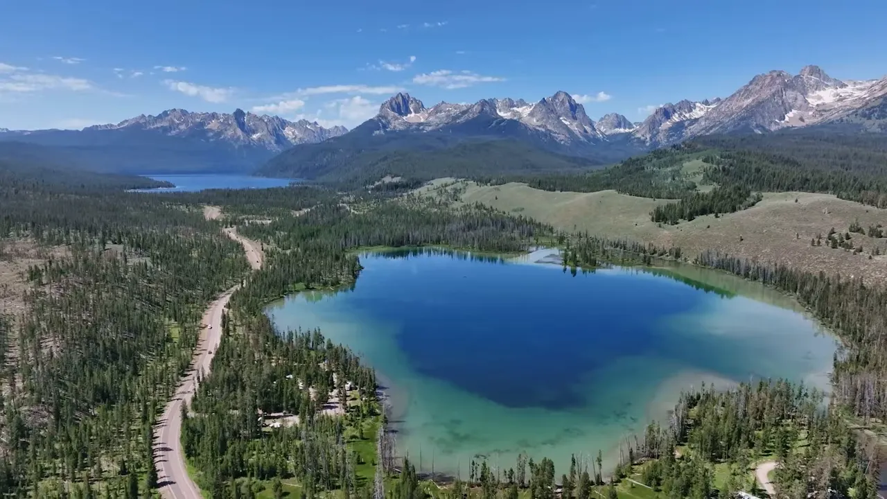 Blue mountain lake surrounded by forest and snowcapped peaks
