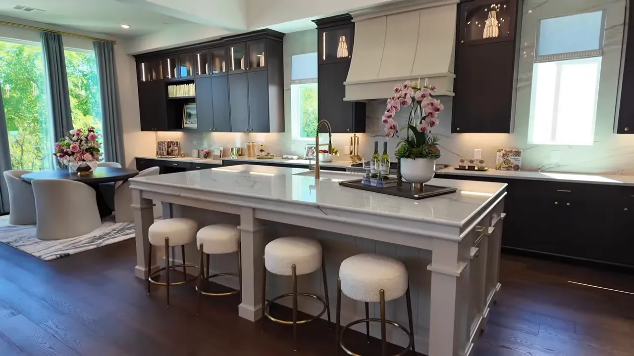 Bright luxury kitchen with large island, dark cabinetry, and seating in Estates at Bristol Valley model home