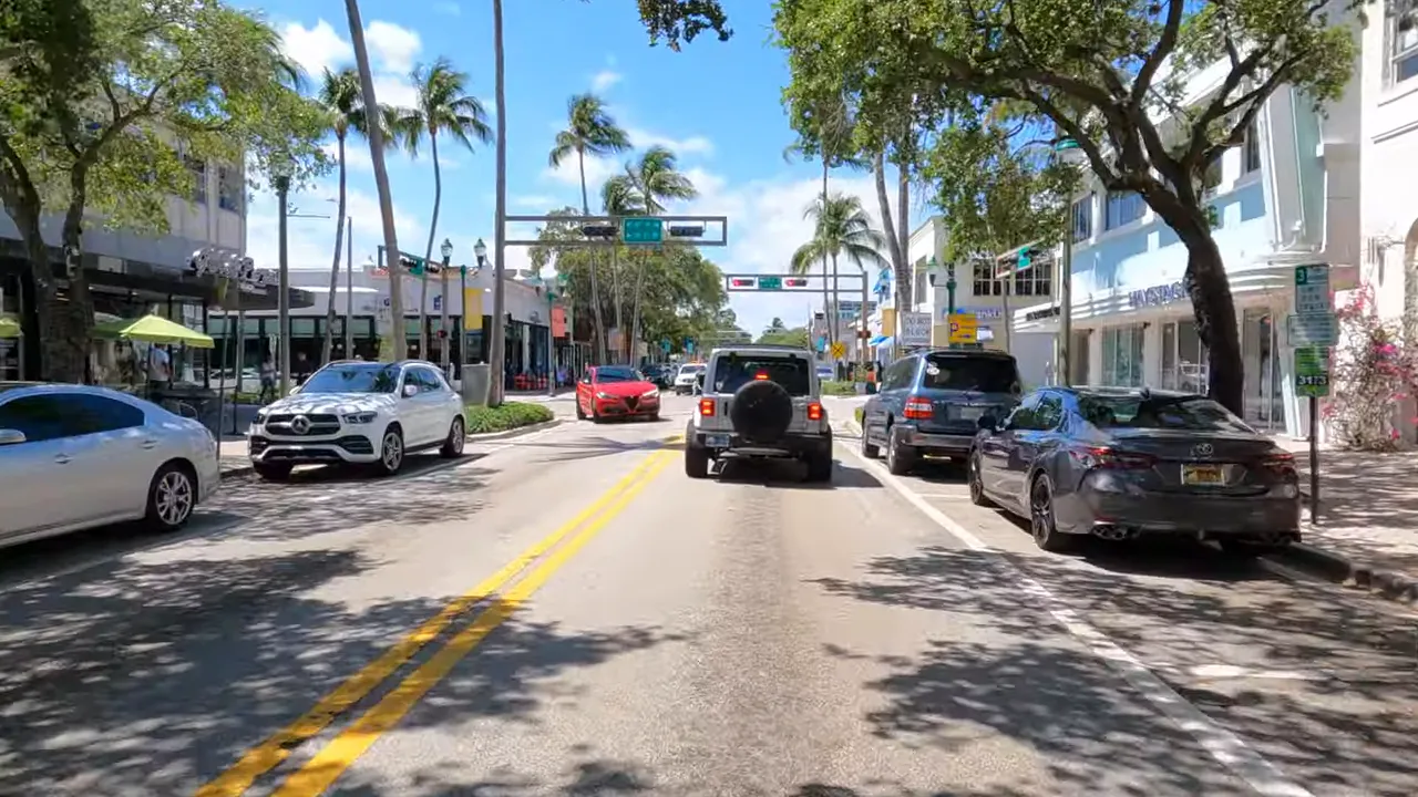 Street view in Boca Raton showing a busy road with cars and palm-lined buildings