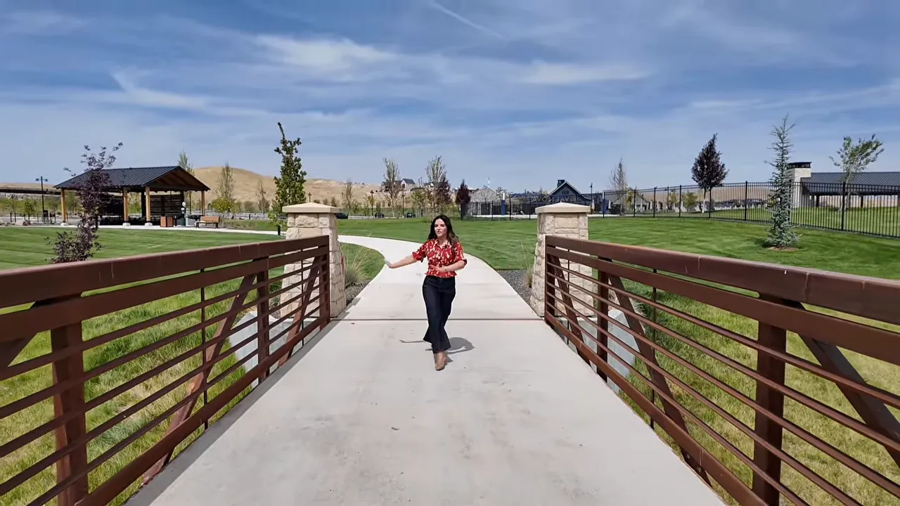 Pedestrian bridge with metal rails crossing landscaped green space