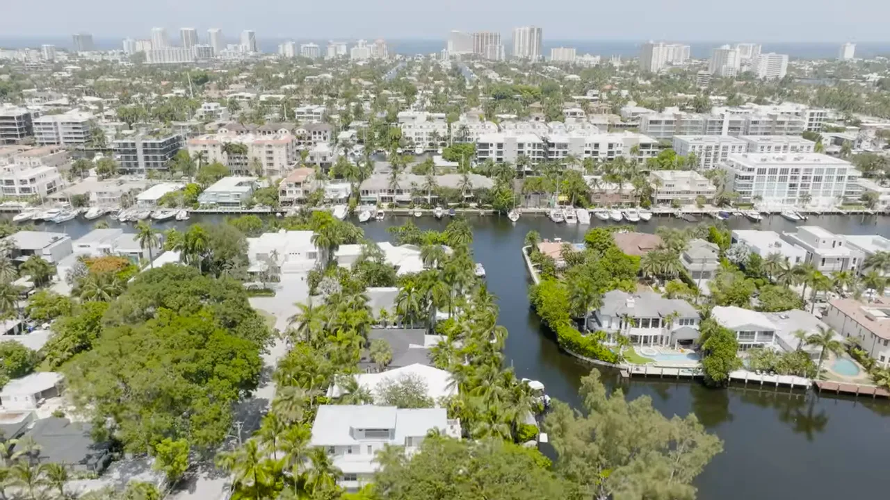 Aerial view of canals and waterfront homes with Fort Lauderdale skyline and ocean in the distance