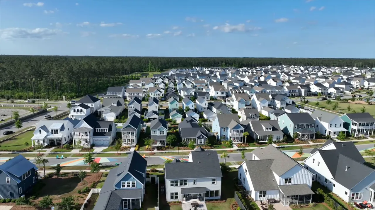 High‑clarity aerial of a suburban neighborhood showing rows of single-family homes, sidewalks, yards and a colorful community street