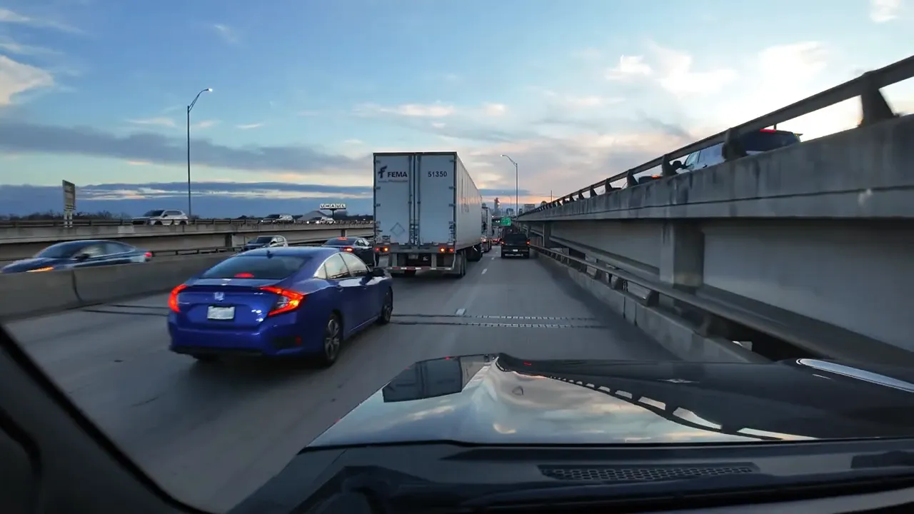 Cars and trucks moving on a highway with visible congestion and long traffic lanes