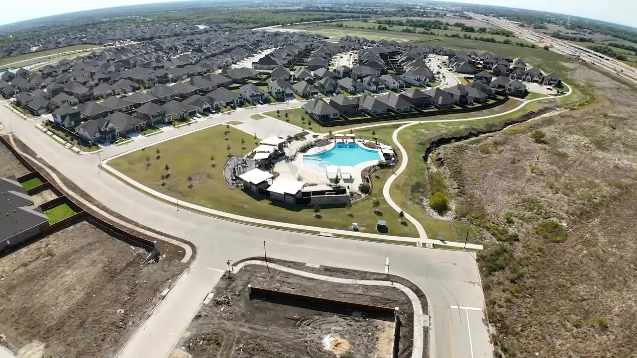 High-resolution aerial photo of the Creekshaw neighborhood with a central resort-style pool, walking paths, and surrounding homes.