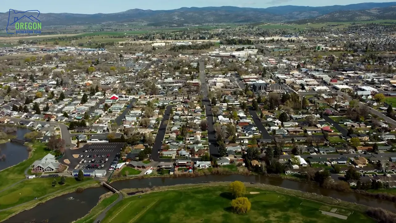 Aerial panorama of an Oregon town with streets, homes, and a river