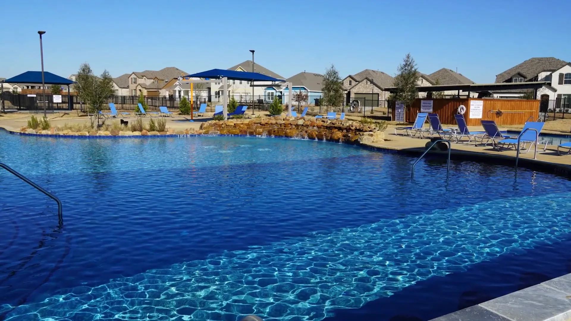 Large resort-style swimming pool with neighborhood homes behind it