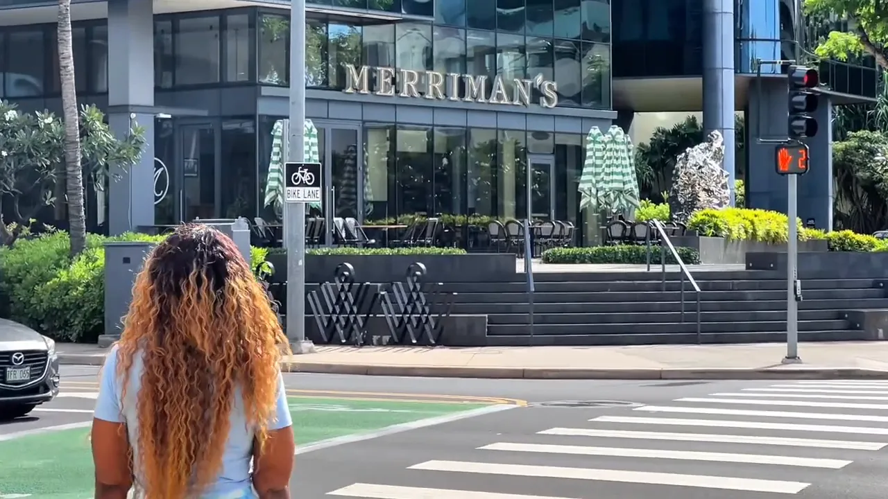 Person walking across a crosswalk in front of the Merriman's storefront in Honolulu