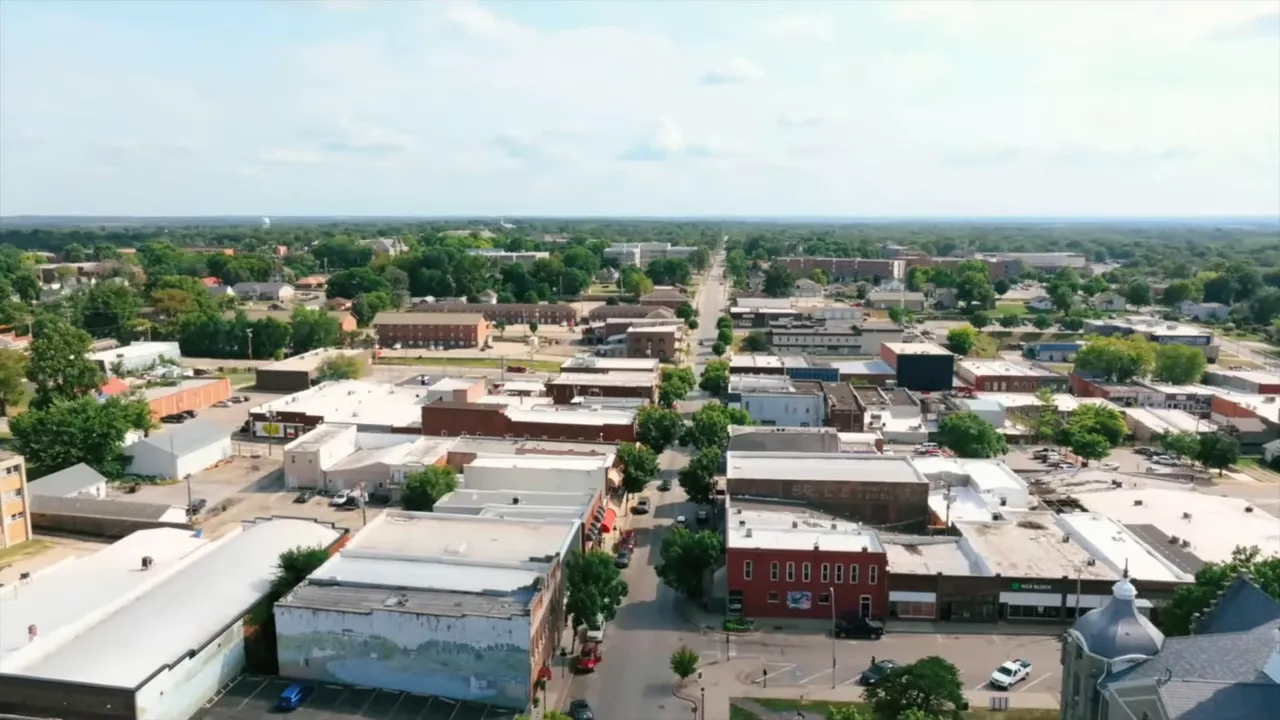 Aerial view of downtown Warrensburg with low-rise buildings, tree-lined streets, and a clear grid layout.
