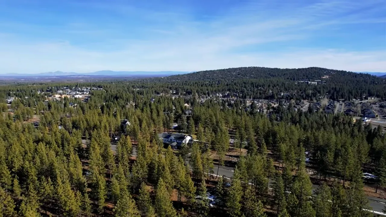 Aerial view of Westgate neighborhood in Bend, Oregon with homes surrounded by pine forest and mountain backdrop