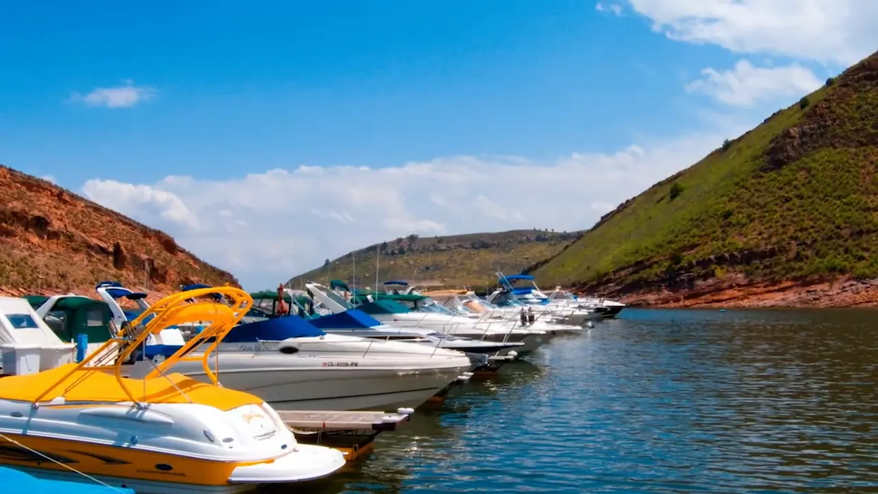 Two people paddle boarding near a small motorboat on a reservoir