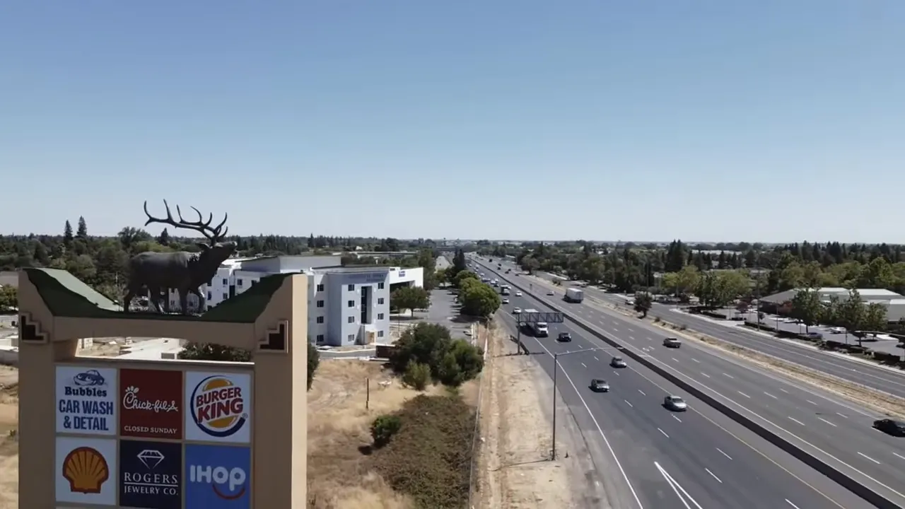 Drone shot of Elk Grove sign with elk statue and the multi-lane highway running alongside suburban development